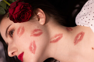 sexy brunette woman with kisses, lipstick marks on her face and neck, with red rose. girlfriend,...