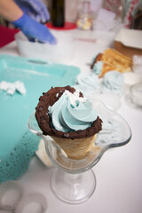 Wafer cones filled with marshmallows. With white and dark chocolate. Nearby zephyr on the table surface.