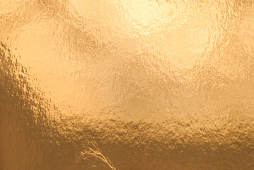 Gold background, texture. Background of gold foil with light reflections. Beautiful transition of...