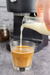 Fototapeta na wymiar Barista pouring milk in capuccino coffee glass