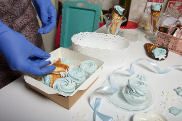 A woman in rubber gloves lays homemade marshmallows in a gift box. Close-up shot.