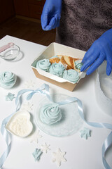 A woman in rubber gloves lays homemade marshmallows in a gift box. Close-up shot.