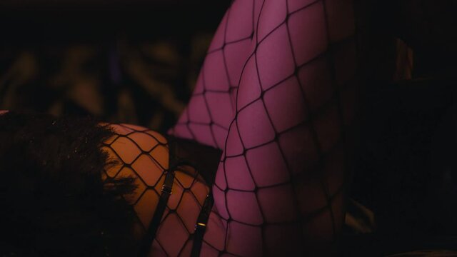 cropped view of sexy woman in fishnet tights turning around on black sofa