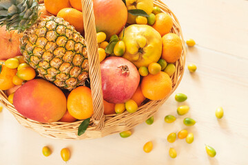 A basket of tropical fruits: pineapple, mango, grapefruit, tangerines, oranges, pomegranates, kumquat on a white background