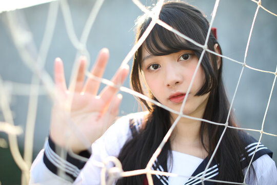 Portrait of Asian japanese high school girl uniform looking with football goal nets