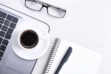 Office desk table with laptop, smart phone, cup of coffee and supplies, on wooden background. Top view with copy space, flat lay.