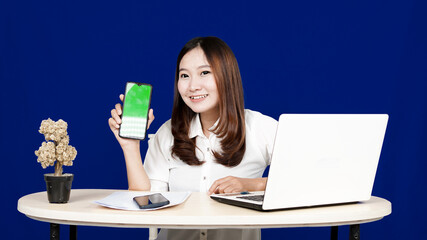 business Asian woman with green screen handphone in workspace isolated blue background