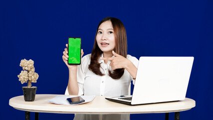 business Asian woman with green screen handphone in workspace isolated blue background