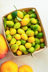 Fresh kumquat in a box on a white table