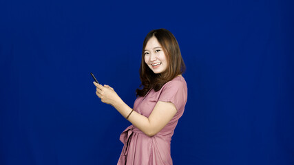 beautiful asian woman smile see handphone isolated blue background