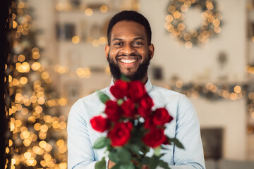 Smiling black man holding roses, giving to camera