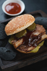 Brisket sandwich with black potato chips and dip on a wooden serving tray, selective focus, vertical shot, close-up