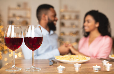 Black man having dinner with woman, focus on wine glasses