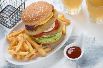 Double fishburger with french fries and beer, studio shot on a white concrete background