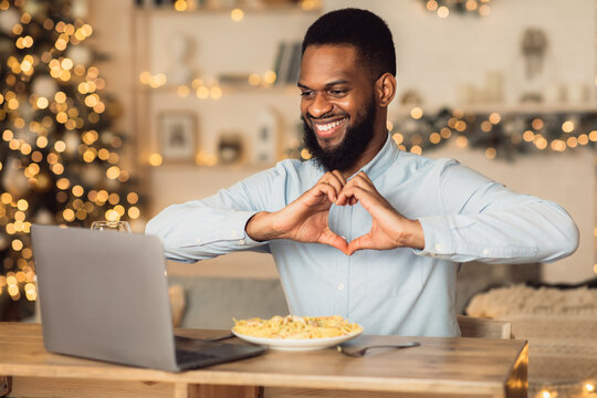 Black man having video call showing heart gesture
