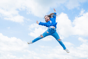 Naklejka na ściany i meble smiling child jumping so high. carefree and joyful. kid fashion style. teenage girl on sky background outdoor. hipster kid jump. happy childrens day. happy childhood. Autumn style