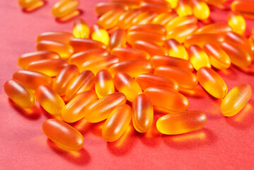 lots of yellow gelatin capsules on a red background. omega viramins, close-up, macro