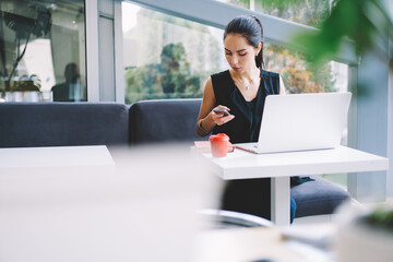 Serious woman using smartphone while working