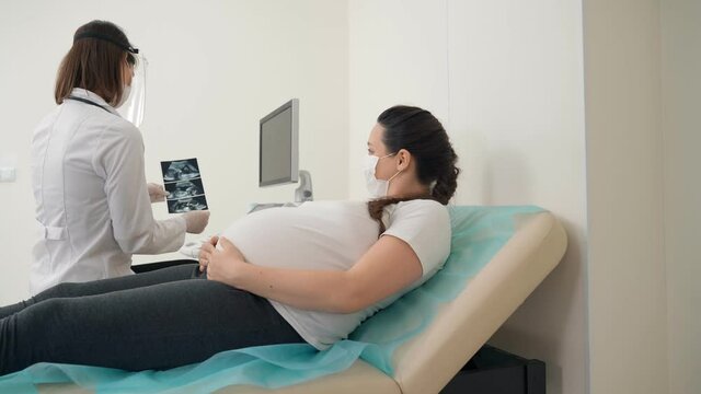 Gynecologist showing ultrasound images for pregnant woman