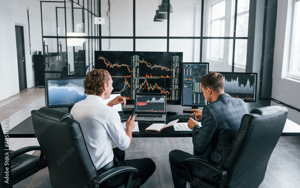 Poster conception of teamwork. team of stockbrokers works in modern office with many display screens