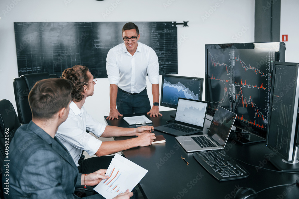 Poster conception of teamwork. team of stockbrokers works in modern office with many display screens