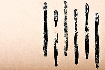 Drawing of silhouettes of toothbrushes in black on a gradient pink and beige background.