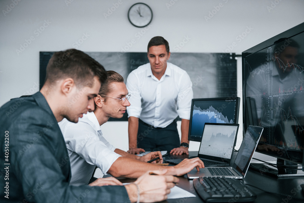 Poster conception of teamwork. team of stockbrokers works in modern office with many display screens