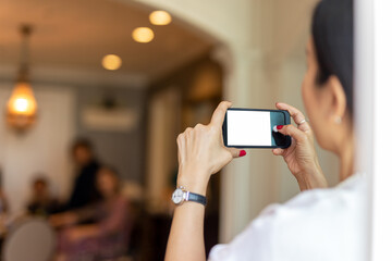 Woman taking picture of her friends at home using cell phone.