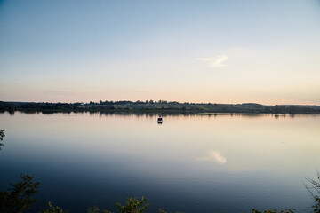 Beautiful lake view during sunset with blue and yellow sky reflection in water. Rural scene. Ecological protection and eco tourism concept. Natural landscape. Isolation in countryside.