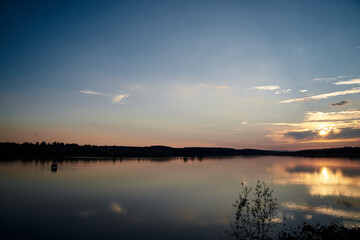 Beautiful lake view during sunset with blue and yellow sky reflection in water. Rural scene. Ecological protection and eco tourism concept. Natural landscape. Isolation in countryside.