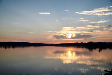Beautiful lake view during sunset with blue and yellow sky reflection in water. Rural scene. Ecological protection and eco tourism concept. Natural landscape. Isolation in countryside.