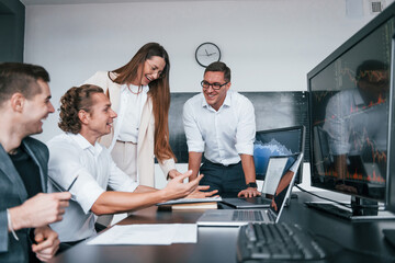 Attention to details. Team of stockbrokers works in modern office with many display screens