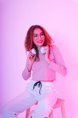 Fototapeta na wymiar Asian beauty girl curly hair with wireless headphone in neon studio.