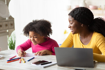 Cute Little Black Girl Drawing In Kitchen Next To Her Mom