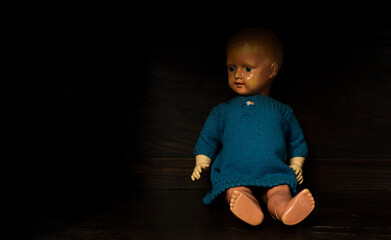 Alte Puppe sitz in einem Holzschrank