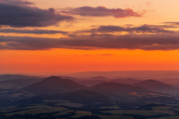 A view of a landscape full of mountains during a golden sunset with the sun on the horizon and a view of the sun from the top of Mount Ondrejnik.