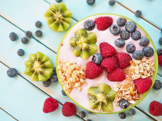 Healthy breakfast - the bowl of oat granola with yogurt, fresh raspberries, blueberries and nuts
