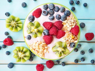 Healthy breakfast - the bowl of oat granola with yogurt, fresh raspberries, blueberries and nuts

