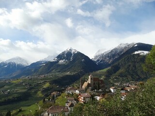 Fototapeta na wymiar Blick auf Schenna in Südtirol von erhöhtem Standort mit Bergpanorama im Hintergrund bei blauem Himmel mit weissen Wolken