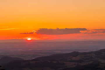 Fototapeta premium A view of a landscape full of mountains during a golden sunset with the sun on the horizon and a view of the sun from the top of Mount Ondrejnik.