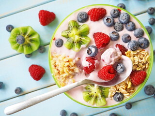 Healthy breakfast - the bowl of oat granola with yogurt, fresh raspberries, blueberries and nuts
