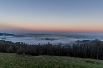 Deep red sky at sunrise with a landscape in which lies a heavy fog over the city.