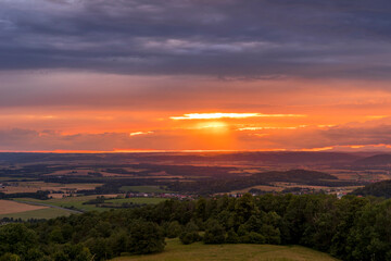The landscape of the Beskydy Mountains from the viewpoint near Jicin during a colorful sunset and dark clouds in the sky and a view of the surrounding landscape.