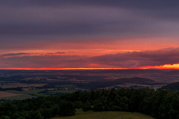 The landscape of the Beskydy Mountains from the viewpoint near Jicin during a colorful sunset and dark clouds in the sky and a view of the surrounding landscape.