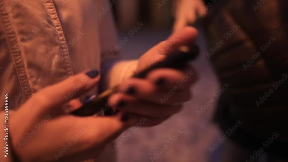 Poster using phone in the hands of a girl on street of night city. scrolls screen with fingers, terminates 