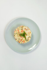 Top view of Russian traditional holiday Olivier salad. Dish of boiled vegetables dressed with mayonnaise sauce. Christmas New Year cold dish served on gray plate. Object isolated on background.

