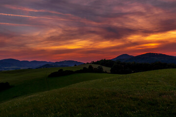 Beskydy mountains Kozlovice landscape with lots of hills and mountains on the horizon and colorful sunset with lots of clouds in the sky.