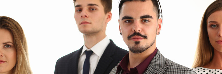 Waist up portrait of trendy confident guy in suit with two women and man in classic wear isolated on white background