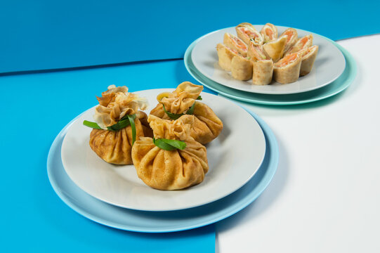 Side view of Two types of Russian traditional crepes. Blini with meat and salmon fish. Christmas holiday dishes. New year serving. Thin Russian pancakes served on blue colorful abstract background. 
