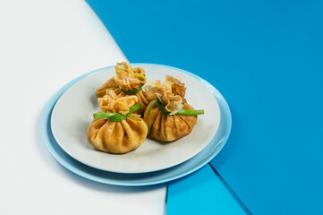 Close up of Holiday Russian starter dish blini with minced meat inside. Traditional crepes appetizer with fresh spring onion scallions. Delicious new year Christmas dish on blue abstract background
